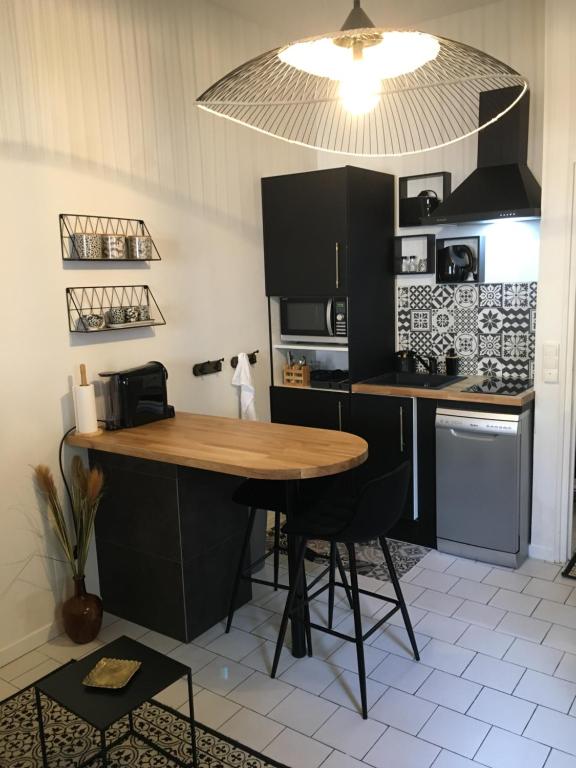 une cuisine avec une table en bois et des armoires noires dans l'établissement Studio 15, à Honfleur