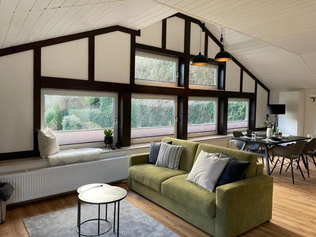 ein Wohnzimmer mit grüner Couch und einigen Fenstern in der Unterkunft Am Taubenhaus FEWO Turteltäubchen NEU in Traben-Trarbach
