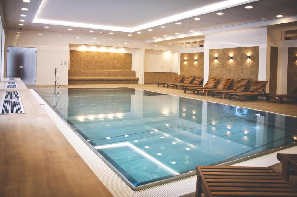 a large swimming pool in a building with chairs at Apartmán Rezidence Moser-free parking garage in Karlovy Vary