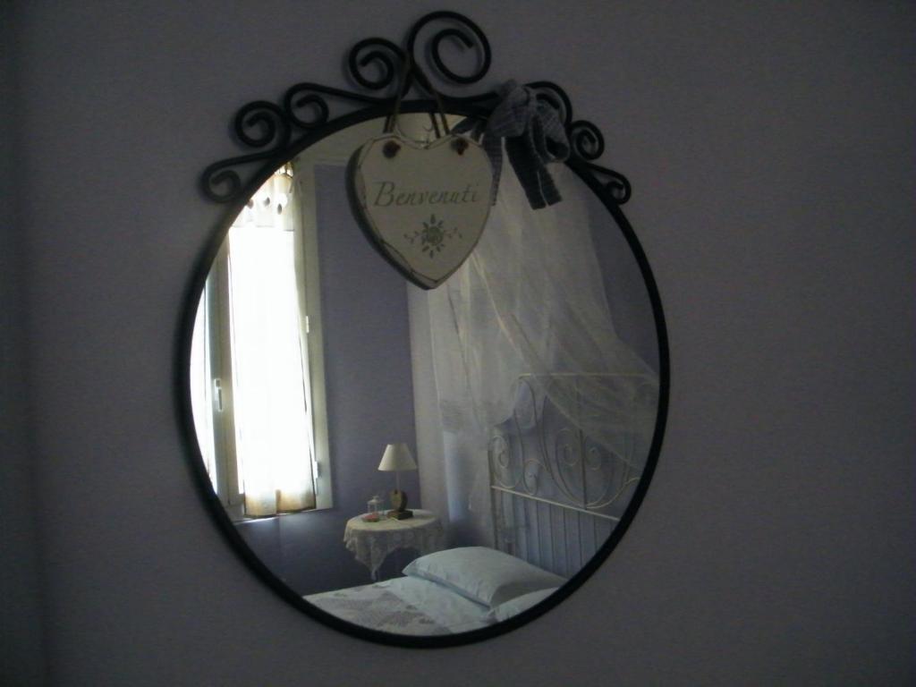 a mirror reflecting a bedroom with a bed and a window at Appartamento Vacanze I Provenzali in Bordighera