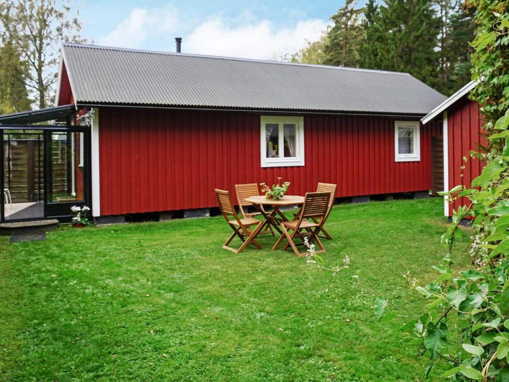 Ce cottage rouge comprend une table et des chaises dans la cour. dans l'établissement Holiday home Byxelkrok IV, à Byxelkrok