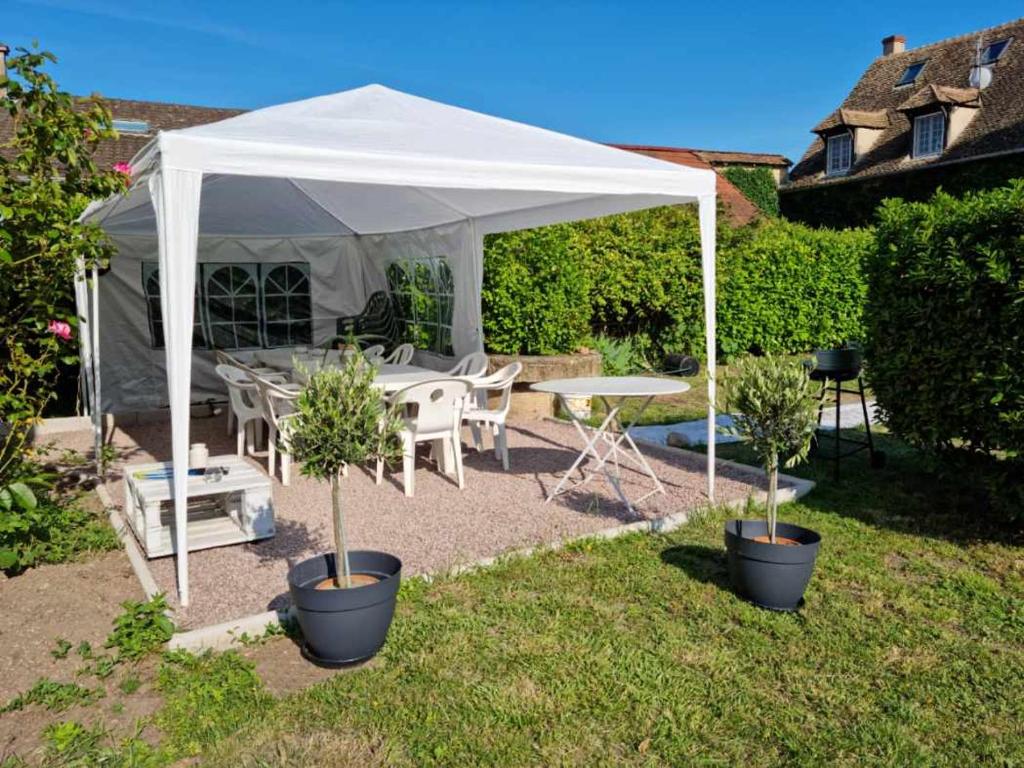 una tienda blanca en un patio con dos macetas en Gîte avec piscine 14 personnes en Gigny-sur-Saône