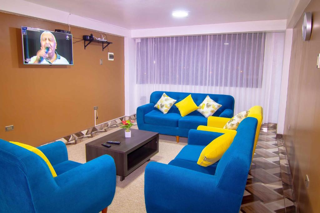 a living room with blue couches and a tv at Departamentos KIRI para familias o empresas que viajan en grupo cerca al Aeropuerto Juliaca in Juliaca