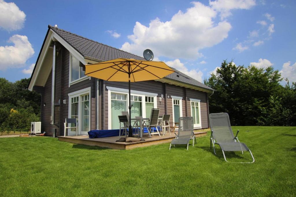 a house with a table and chairs and an umbrella at Holiday house at the Schaalsee, Zarrentin in Zarrentin