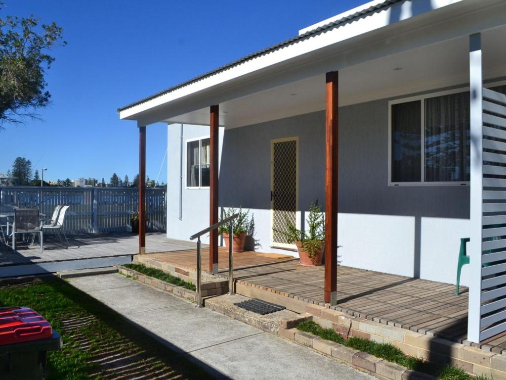 a white house with a porch and a patio at 2 Rockpool Road in Tuncurry