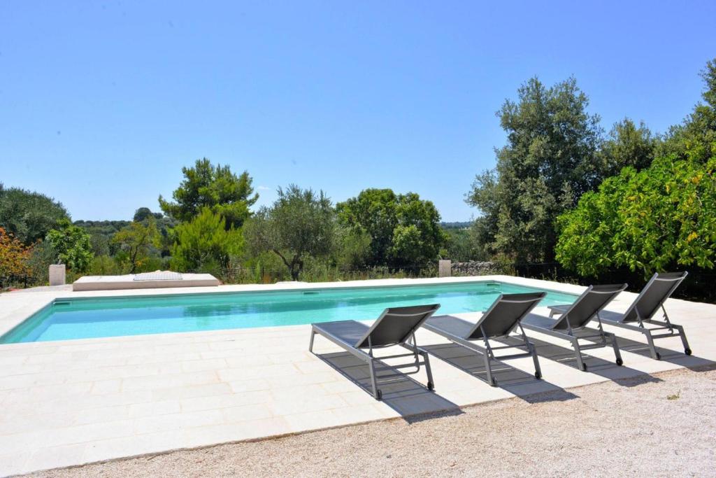 una piscina con sedie e alberi sullo sfondo di Trullo, Cisternino a Cisternino