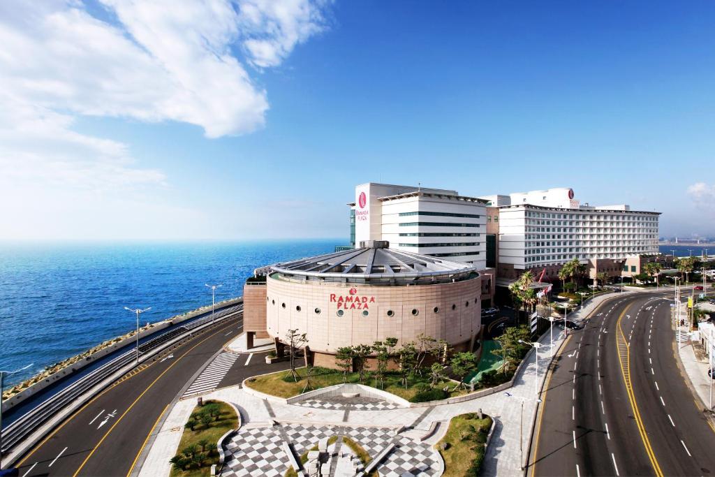 a building next to the ocean and a highway at Ramada Plaza by Wyndham Jeju Ocean Front in Jeju