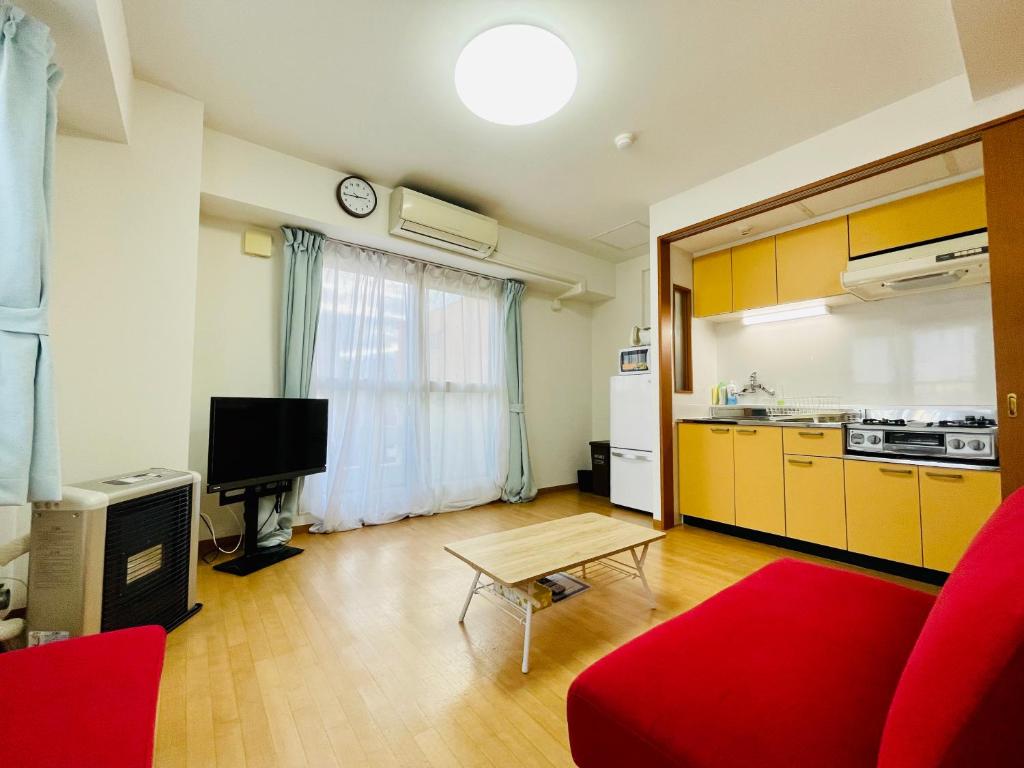 ein Wohnzimmer mit einem roten Sofa und einer Küche in der Unterkunft 9-1広い室内で水廻りも綺麗 ｻｰﾋﾞｽｱﾊﾟｰﾄﾒﾝﾄ札幌大通西14 ﾈｯﾄ使い放題 in Sapporo