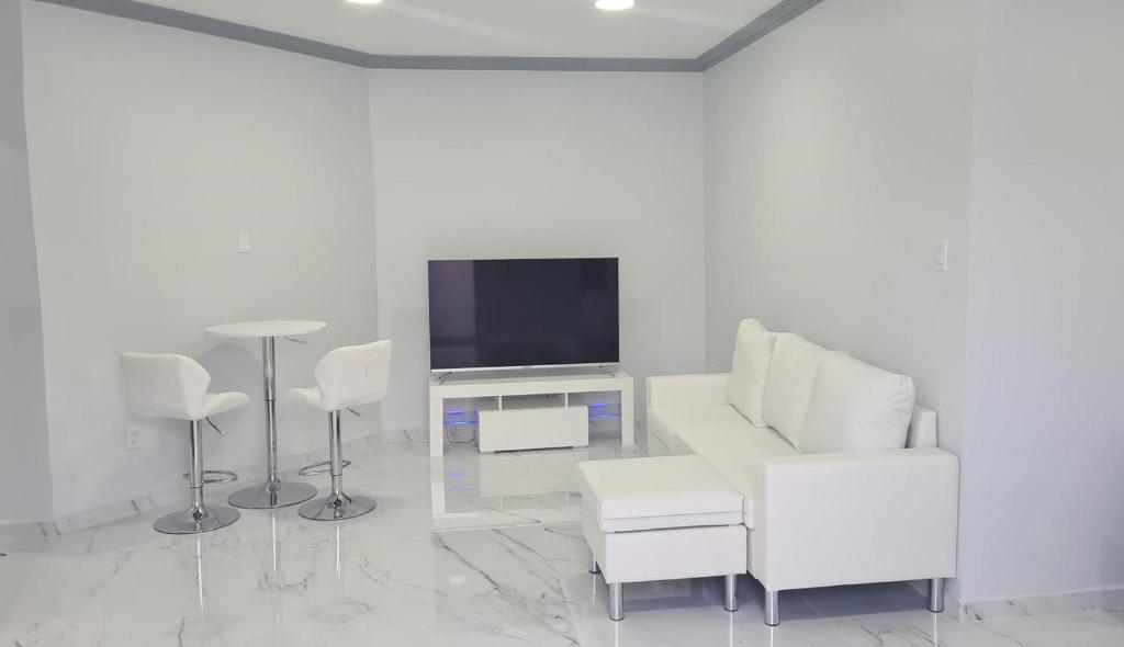 uma sala de estar com mobiliário branco e uma televisão de ecrã plano em New Modern Apartment em Willemstad