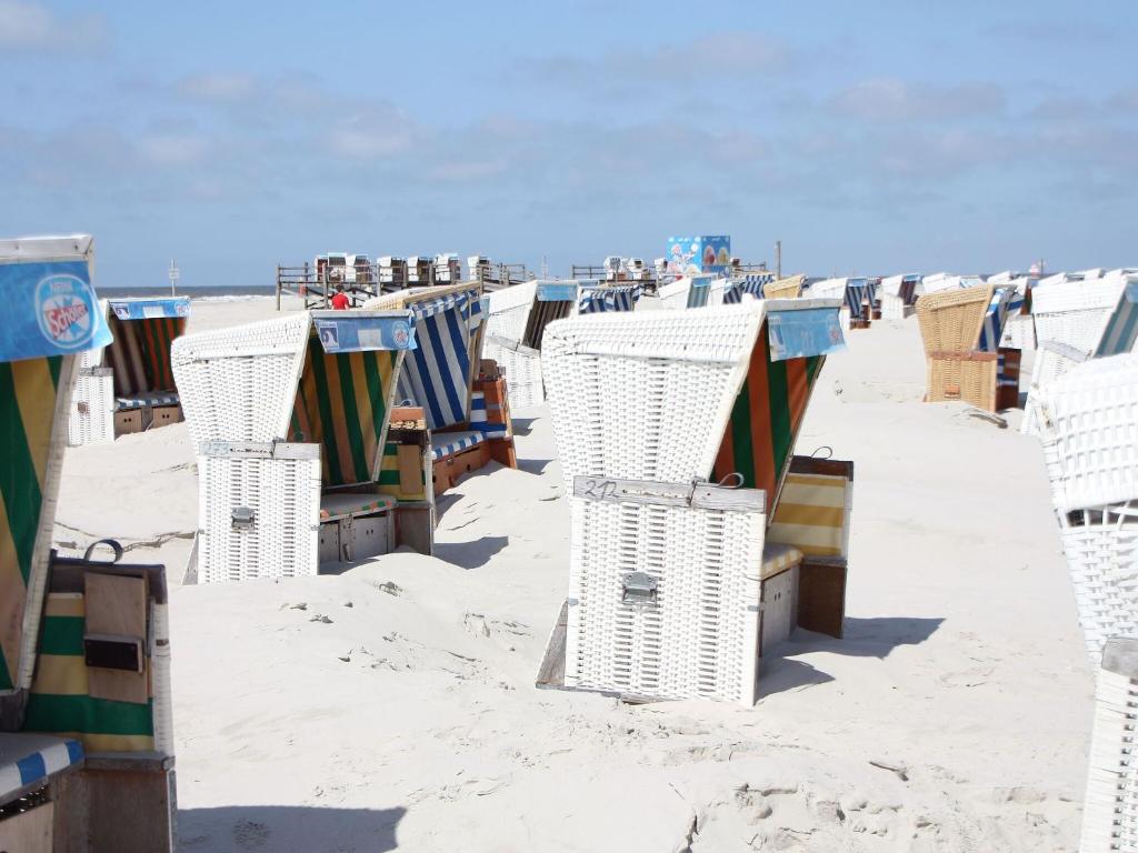 加尔丁Ferienhaus in Garding的沙滩上的一排沙滩椅