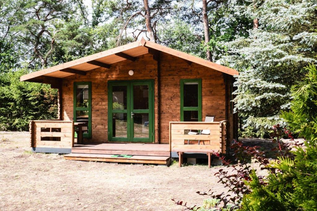 a small wooden cabin with a green door and two chairs at Holiday Home near Baltic Sea and Lake Wise ka in Kodrąb