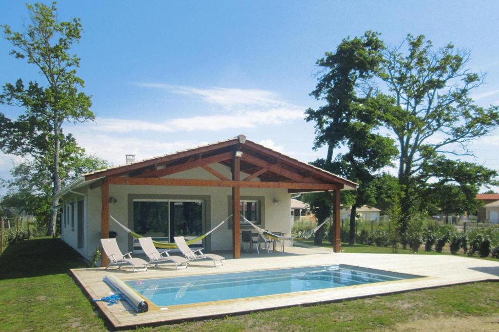 une maison avec une piscine et deux chaises longues dans l'établissement Holiday home with pool, à Grayan-et-lʼHôpital