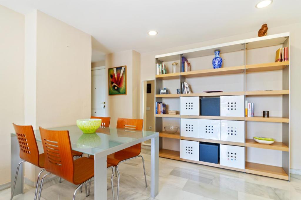 a dining room with a glass table and orange chairs at Benalmadena with seasonal pool & parking near the beach in Arroyo de la Miel