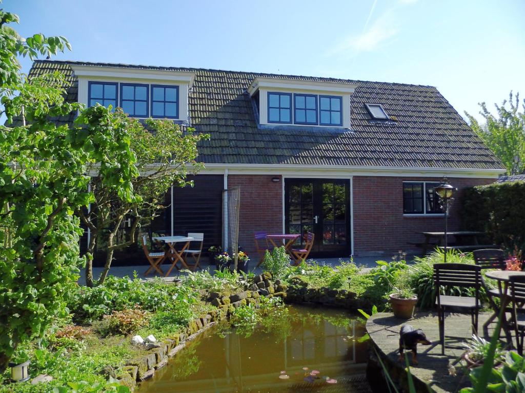 a house with a pond in front of it at 't Laaisterplakky in Oude Bildtzijl