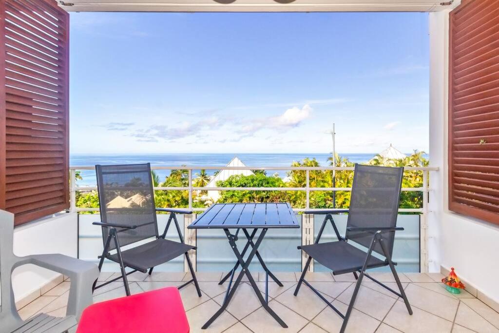 a balcony with a table and chairs and a view of the ocean at Océanides - studio rénové avec magnifique vue mer - Saint-Gilles-Les-Bains in Saint-Gilles les Bains