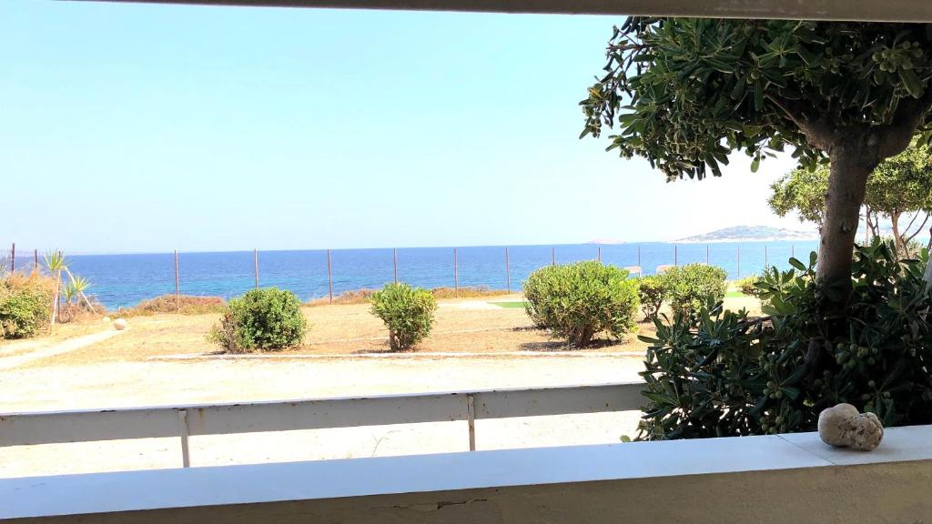 a teddy bear sitting on a bench looking out at the ocean at Vravrona Beach Apartments in Artemida