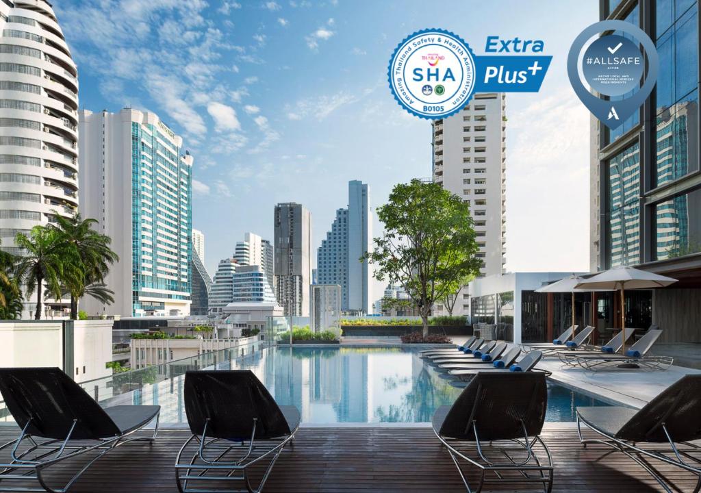 a swimming pool with chairs and a city skyline at Novotel Bangkok Sukhumvit 20 in Bangkok