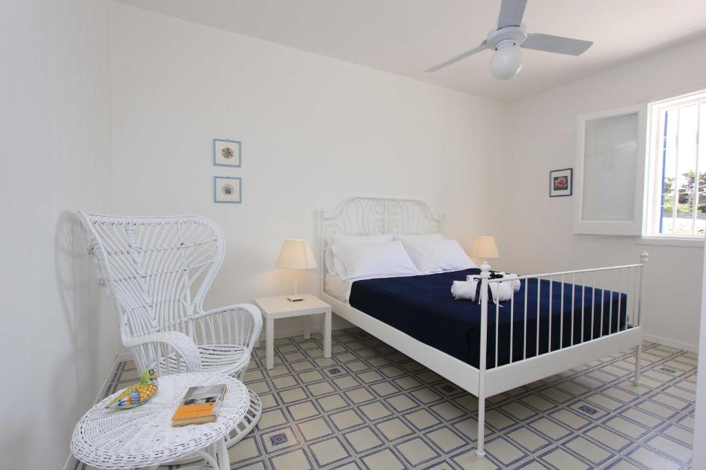 マリーナ・ディ・ラグーザにあるSud Est Le Case di Elisaの白いベッドルーム(ベッド1台、ロッキングチェア付)