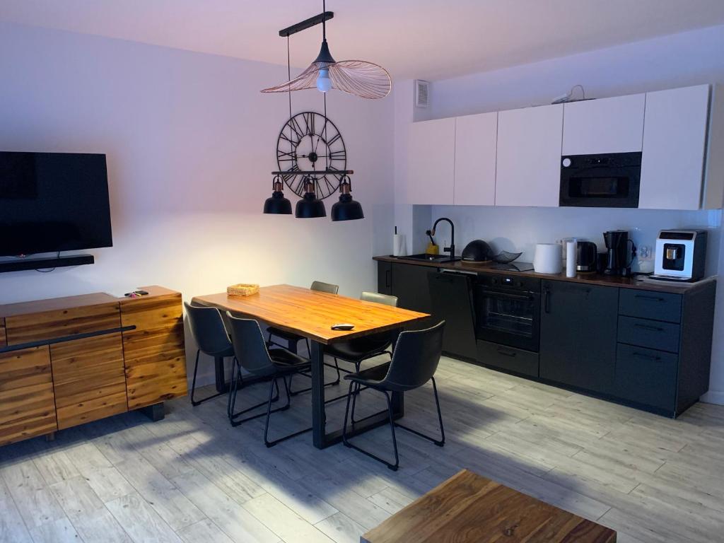 a kitchen with a wooden table and chairs in it at Apartament na Leśnej in Pobierowo