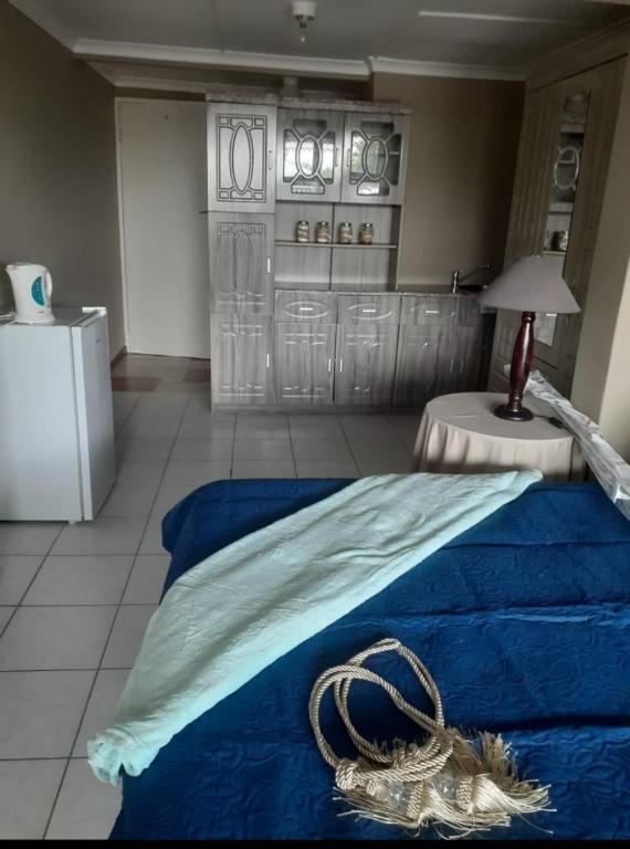 a bedroom with a bed with a blue blanket and a table at NATS Overnight Accommodation Room One Double bed in De Aar