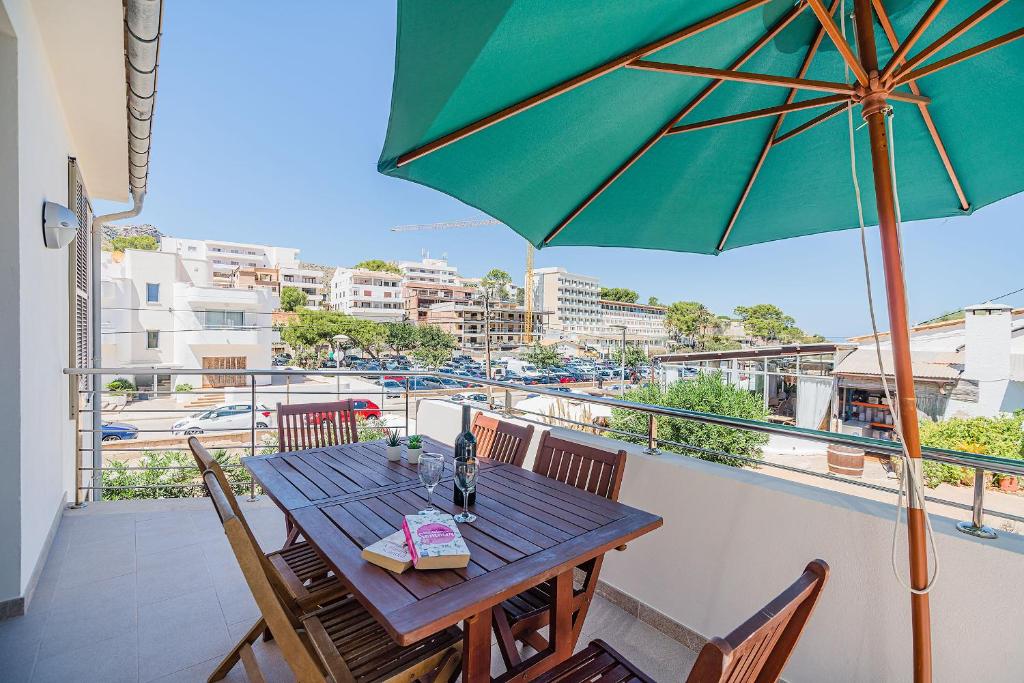 Una mesa con una sombrilla verde en un balcón. en Molins 5, en Cala de Sant Vicent