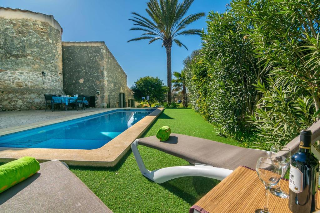 un patio trasero con piscina y una mesa con copas de vino en Es Molí Can Torres, en Sineu