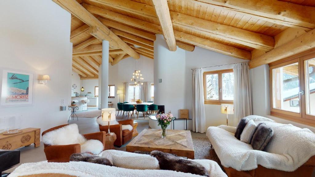 uma sala de estar com tectos em madeira e uma mesa em Funtanella em Samedan