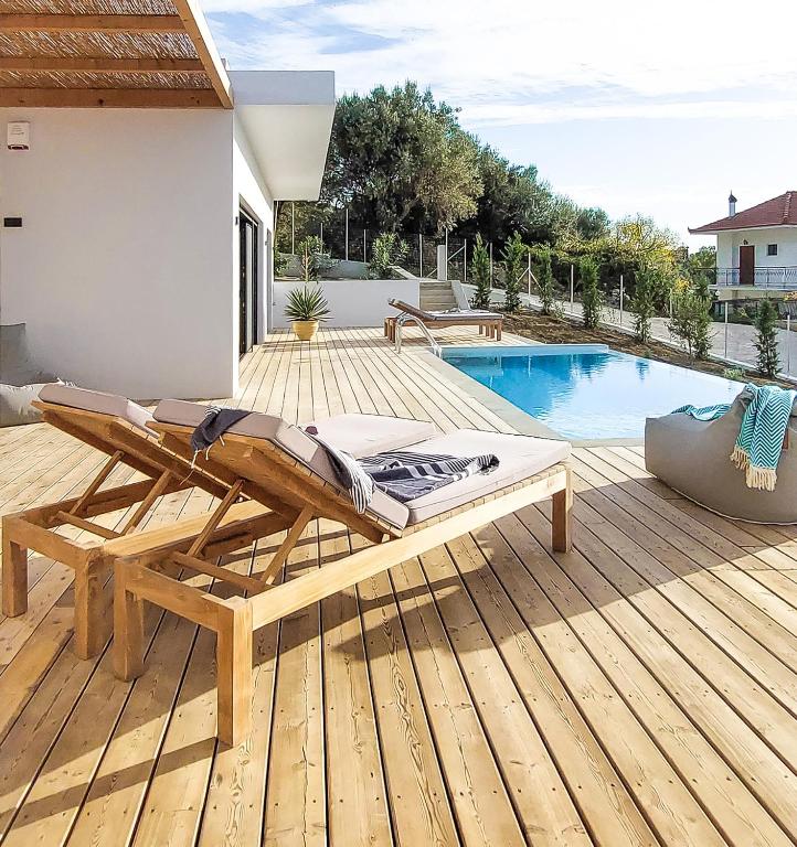 a wooden deck with a chaise lounge next to a swimming pool at Villa Oneiro in Paleros