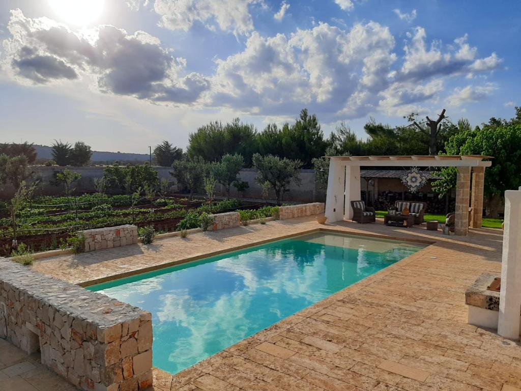 una piscina en un patio trasero con cenador en La Cuccuvascia pool house, en Alessano