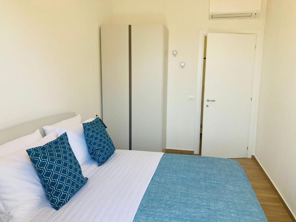 1 dormitorio con 1 cama con almohadas azules y blancas en MALU LUXURY APARTMENTS, en Rímini