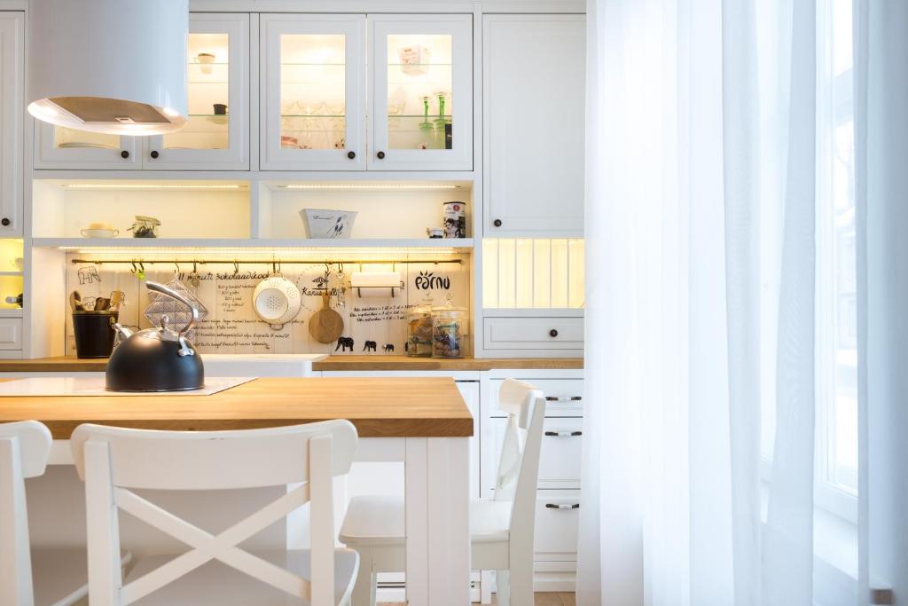 - une cuisine avec des placards blancs, une table et des chaises dans l'établissement Karusselli Apartment, à Pärnu