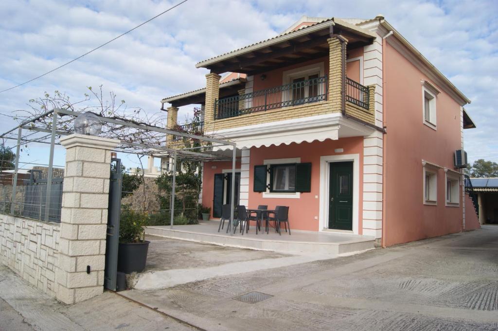 a small pink house with a balcony and a table at Stefanos' Apartment in (( Litherés ))