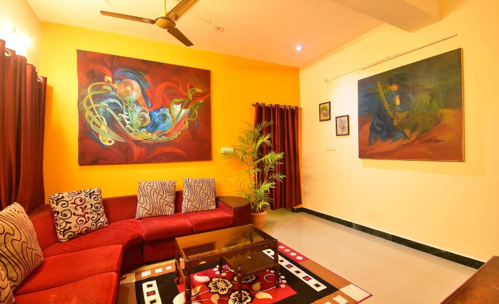 a living room with a red couch and a painting at villa Freddy in Puducherry