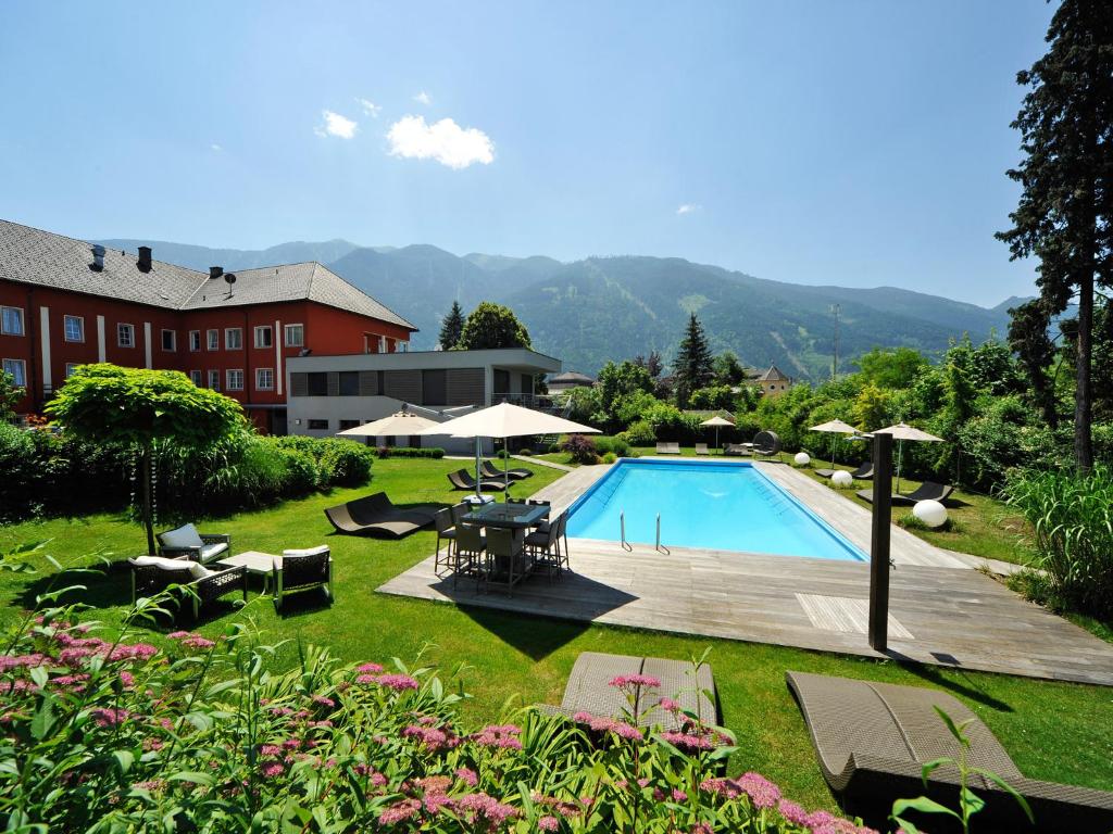 a swimming pool with chairs and tables and umbrellas at Hotel Ertl & mexican cantina salud in Spittal an der Drau