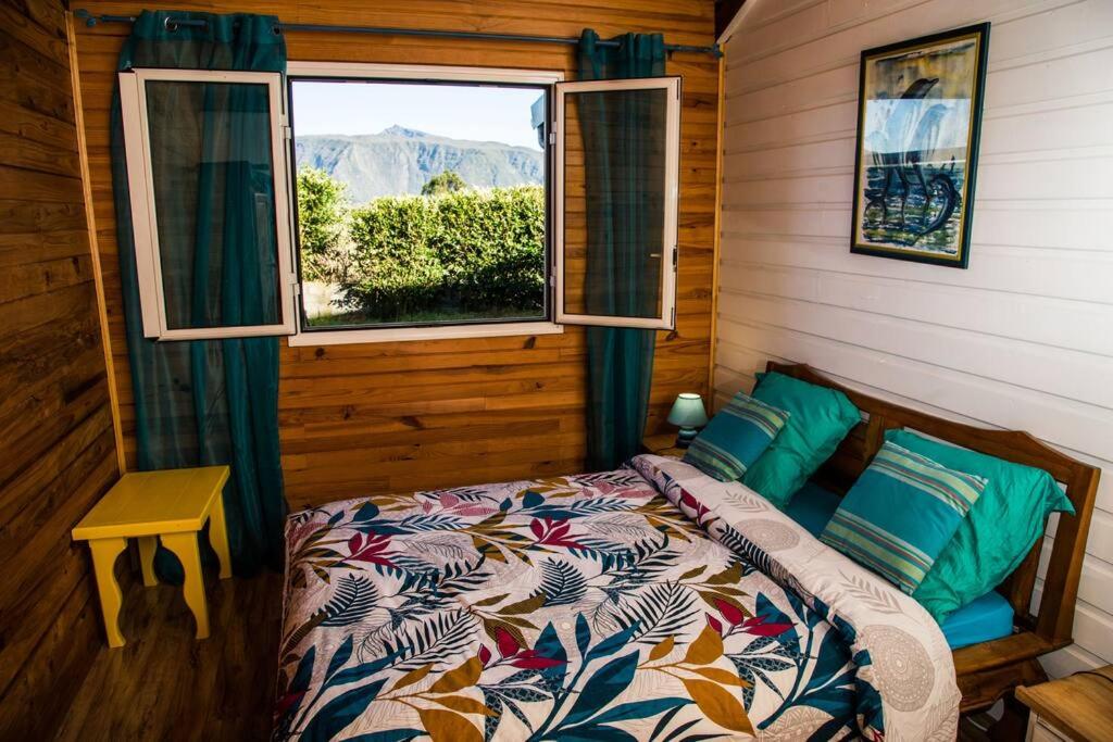 a bedroom with a bed and a window at Chalet des Hauts- Vue piton des neiges in Le Tampon