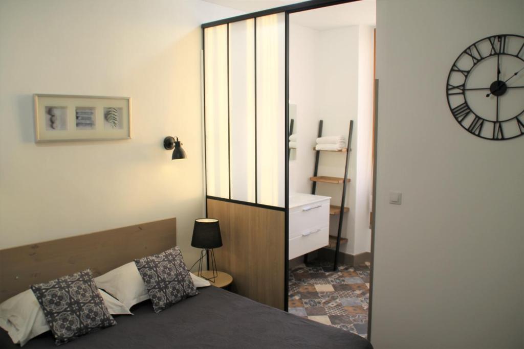 カストルにあるオテル リヴィエールのベッドルーム1室(ベッド1台、壁掛け時計付)