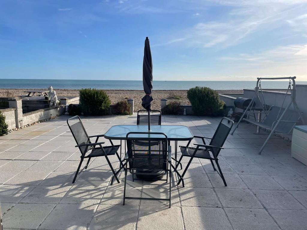 a table with chairs and an umbrella on a patio at Beachfront Bliss Stylish Retreat in Pevensey