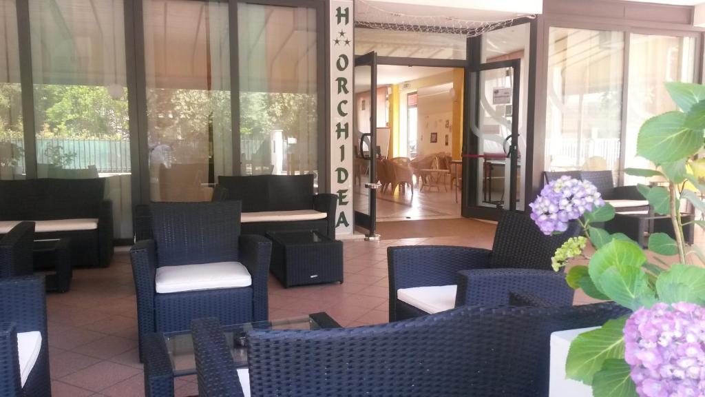 ein Restaurant mit blauen Stühlen, Tischen und Blumen in der Unterkunft Hotel Orchidea in Cesenatico
