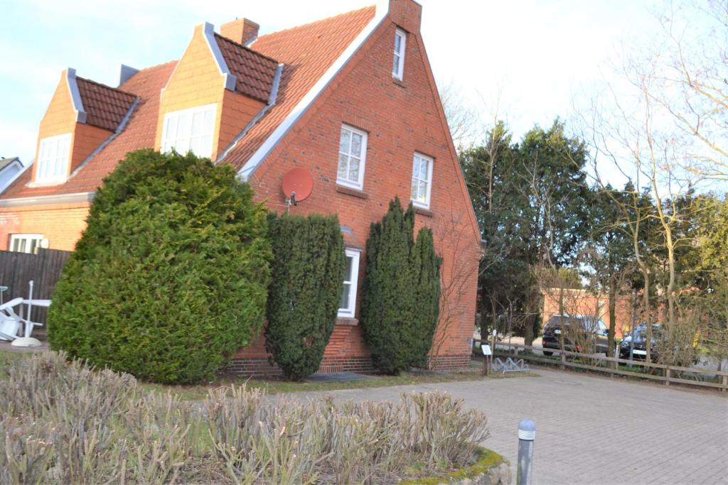 een groot rood bakstenen huis met struiken ervoor bij Nordlicht in Wyk auf Föhr