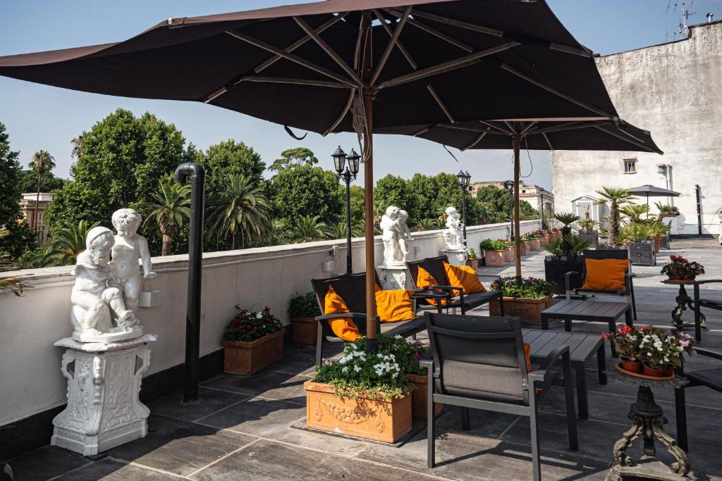 Hotel del Real Orto Botanico في نابولي: فناء في الهواء الطلق مع كراسي ومظلة