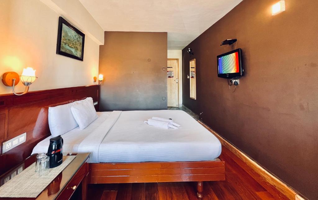 a hotel room with a bed with a tv on the wall at Hotel Jc Grand in Kodaikānāl