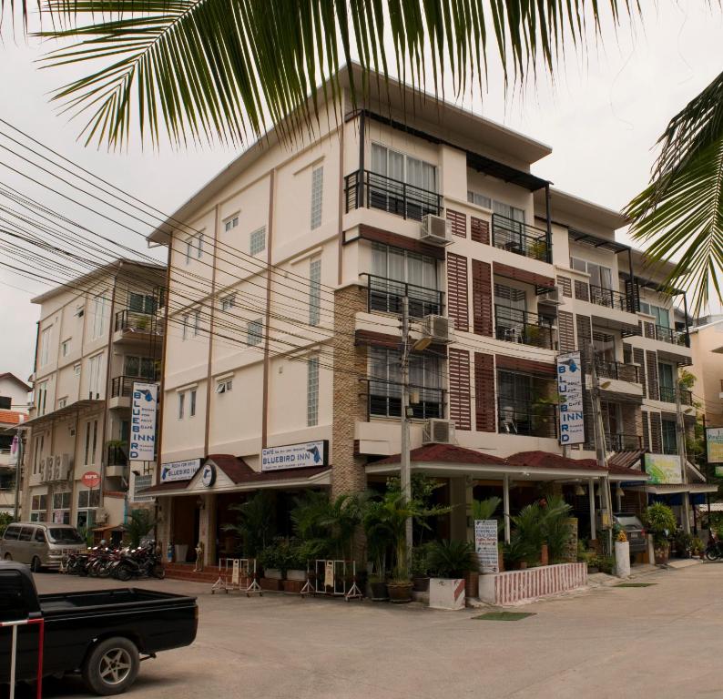 un gran edificio de apartamentos en una calle con aparcamiento en Bluebird Inn Pattaya en Pattaya centro