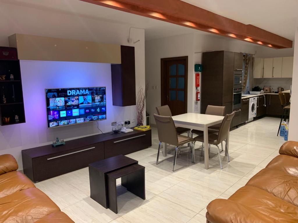 Il comprend un salon doté d'un canapé et d'une table avec une télévision. dans l'établissement XL Bugibba Home, à San Pawl il-Baħar