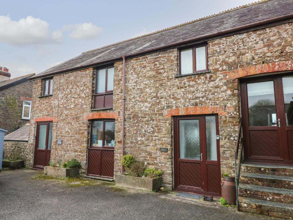 a brick house with brown doors and windows at Barn Cottage in Bude