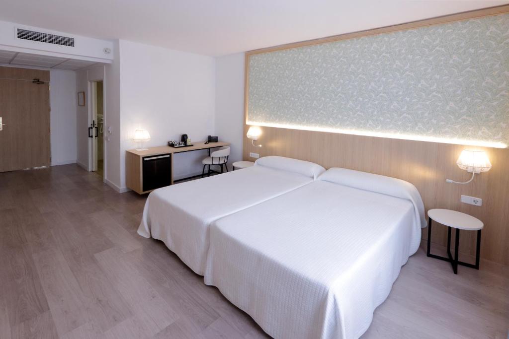 a bedroom with a white bed and a large screen at Sercotel Carlos III in Cartagena