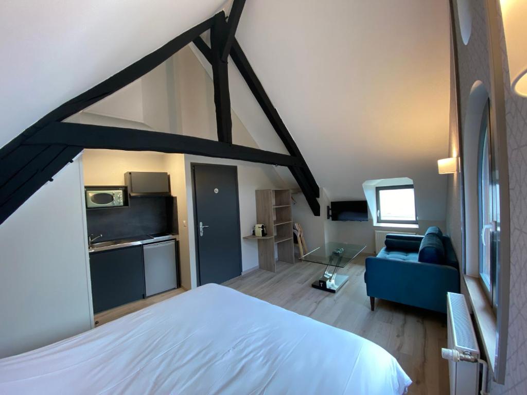 sypialnia z białym łóżkiem i niebieską kanapą w obiekcie L'Escale du Vexin w mieście Chaumont-en-Vexin