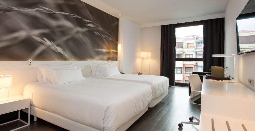 a hotel room with a white bed and a desk at NH Collection Villa de Bilbao in Bilbao
