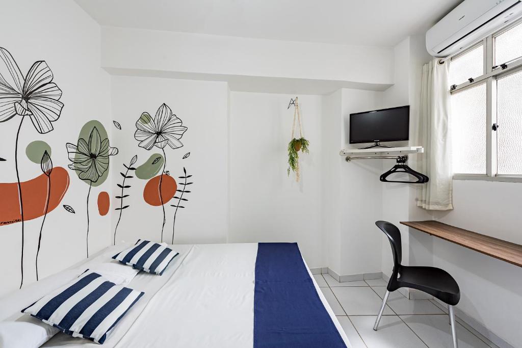 a white room with a bed and a tv at Hotel Prainha in Vila Velha