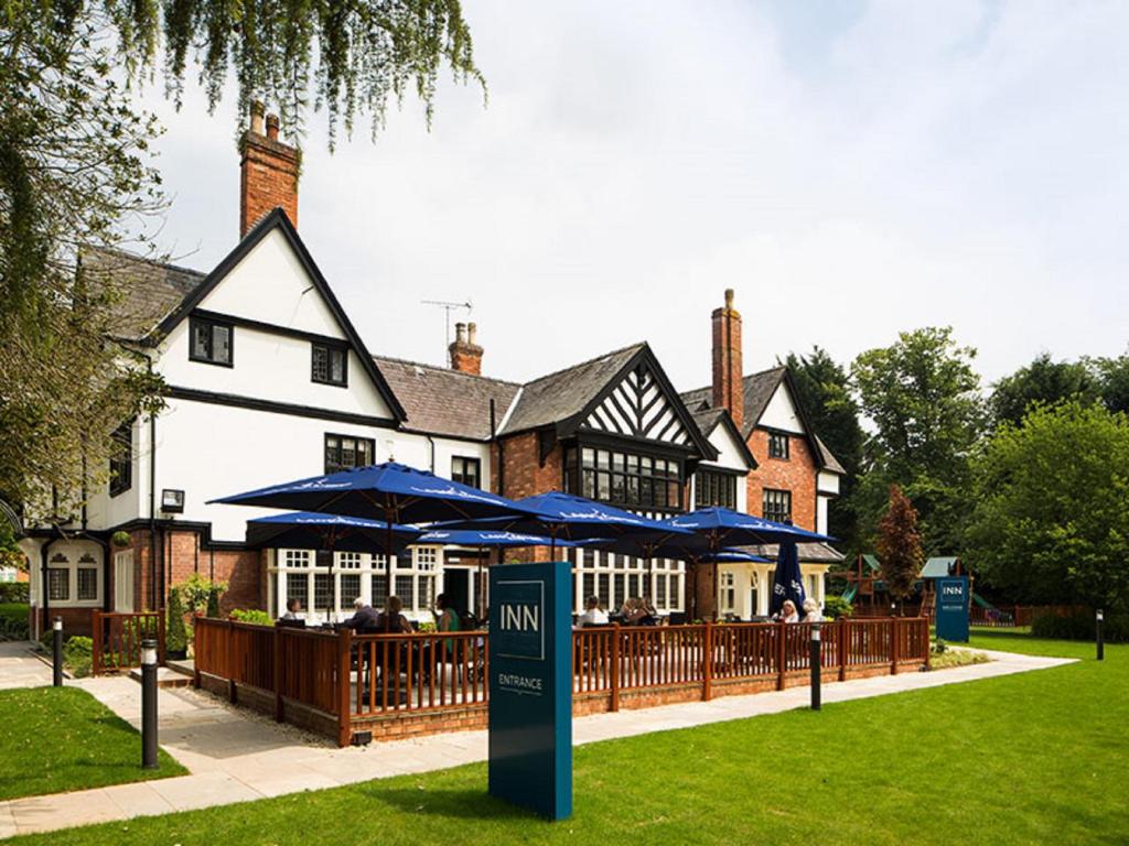 ein Restaurant mit blauen Sonnenschirmen vor einem Haus in der Unterkunft The Inn at Woodhall Spa in Woodhall Spa