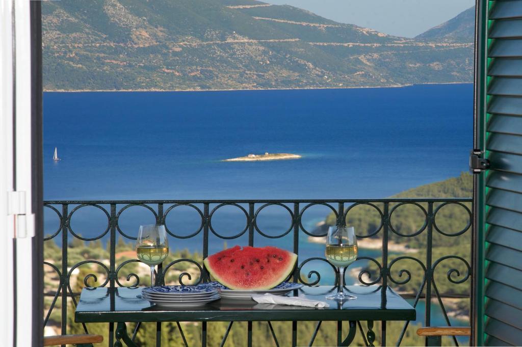 a table with a slice of watermelon on a balcony at Agnantia Bed & Breakfast in Fiskardho